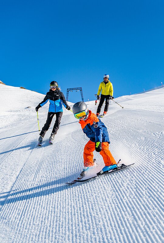 Familie beim Skifahren auf einer präparierten Piste - Link zur Schneesportschule von Heiligenblut 