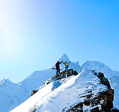 Zwei Skifahrer, die sich ein High Five geben mit dem Großglockner zwischen den Händen - Link zu "Winterurlaubstipps"